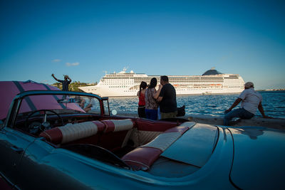 People on boat against clear blue sky