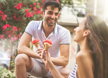 Young man smiling woman holding camera while standing outdoors