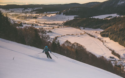 Rear view of person skiing on snowcapped mountain