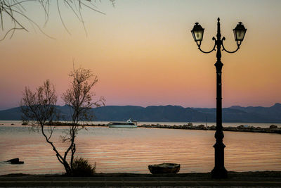 Street light by lake against sky during sunset