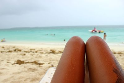 Midsection of woman relaxing on lounge chair at beach