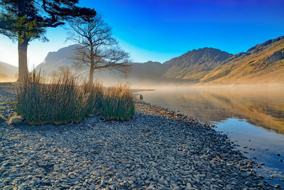 Scenic view of lake and mountains against blue sky