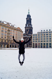 Happy woman jumping at market square against kreuzkirche church during winter