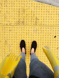 Low section of woman standing on yellow sheet metal