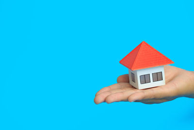 Close-up of hand holding toy against blue background