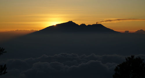 Scenic view of dramatic sky over silhouette mountains during sunset