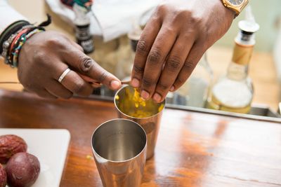 Men scooping the inside of passion fruit into glass