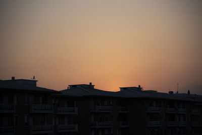 Silhouette buildings against sky during sunset