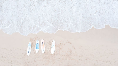 Four surfboard are placed on the sandy beach and sea wave aerial top view from drone, for background 