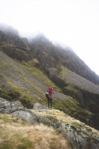 Rear view of man walking on mountain against sky