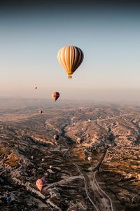 Hot air balloons flying over mountains against sky