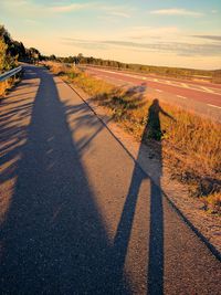 Shadow of person on road against sky during sunset