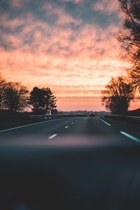 Road seen through car windshield during sunset