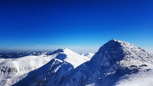 Scenic view of snowcapped mountains against clear blue sky