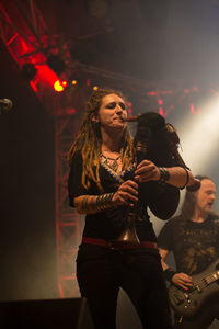 Young woman with arms raised standing at music concert