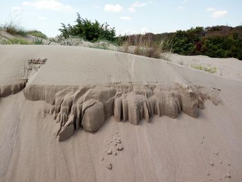 Footprints on sand at beach against sky