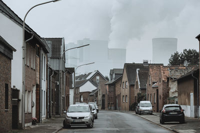 Cars on street amidst buildings in city against sky