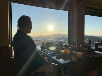 Rear view of man standing by glass window in restaurant