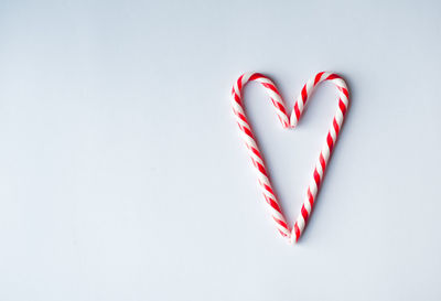 Candy canes arranged in a heart shape on a plain white background.