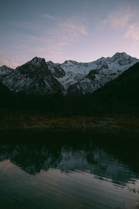 Scenic view of lake by mountains against sky during sunset