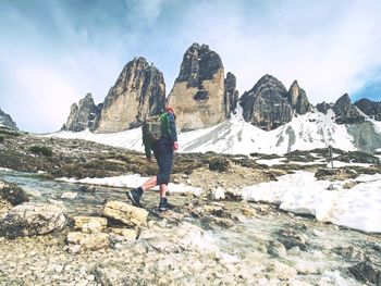 Hiker man with backpack crossing stream on stones in dolomiti mountains. hiking and leisure theme