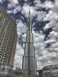 Low angle view of skyscrapers against cloudy sky