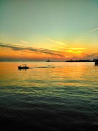 Silhouette boat sailing in sea against sky during sunset