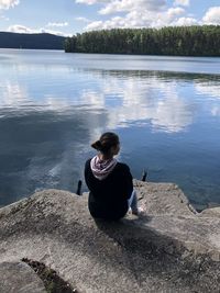 Rear view of man sitting on lake