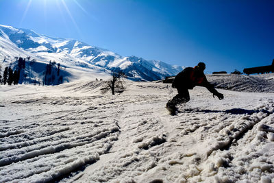 Man skiing on snowcapped mountain against clear sky