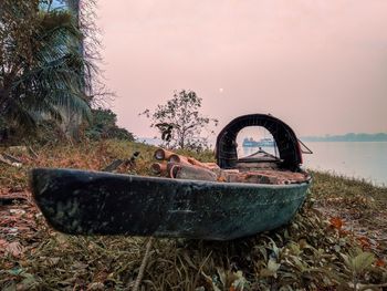 Old boat on river side against sky