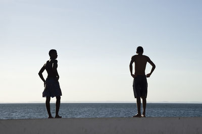 Full length of men standing on beach against clear sky