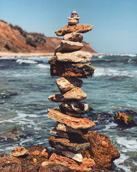 Stack of stones on rock at beach against sky