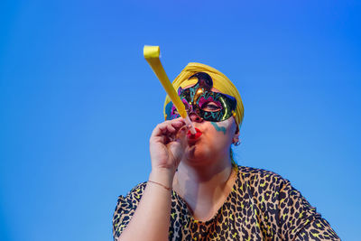 Low angle view of woman playing tambourine against sky