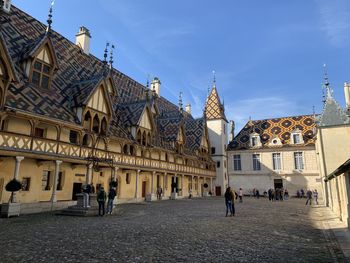 People outside buildings in city against sky