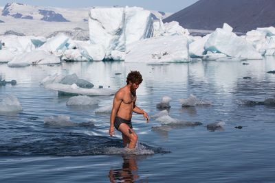 Full length of shirtless man standing in lake