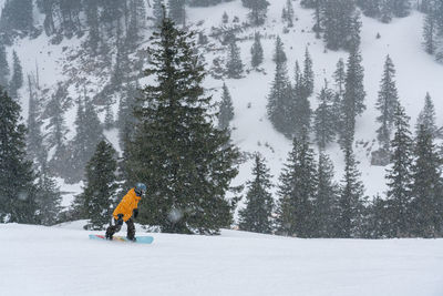 Full length of man snowboarding on snow covered land during winter