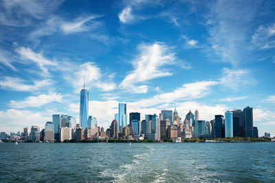 Modern cityscape by river against sky