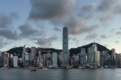 Sea by modern buildings against sky