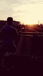 Rear view of man in city at sunset