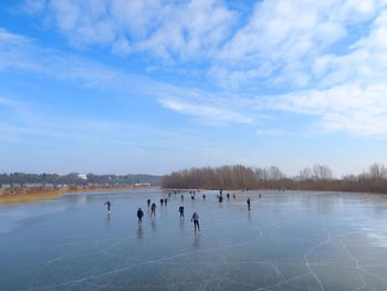 People skating on ice rink against blue sky