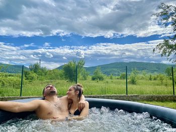 Couple kissing by water against sky