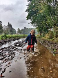 Full length of woman on wet road during rainy season