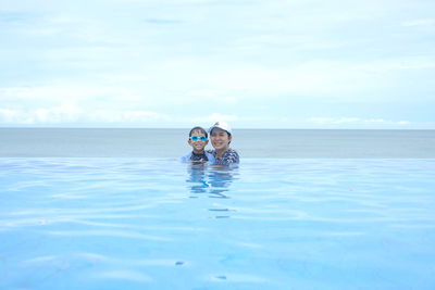 Happy family on swiming pool behind beach in summer