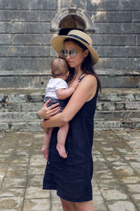 Mom in the hat and the sunglasses is holding his son