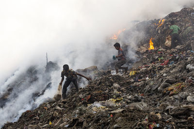 Boys on garbage burning at junkyard