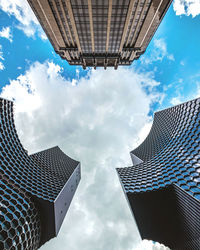 Low angle view of modern buildings against cloudy sky