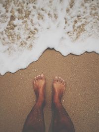 Low section of man on sand by water at beach