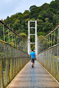 Rear view of boy walking on footbridge