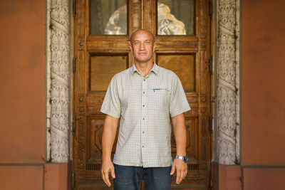 Bald middle-aged man smiling happy walking in the city against the background