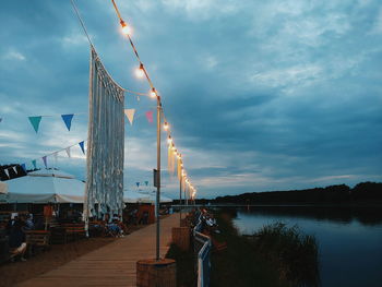 Sailboats on pier at lake against sky